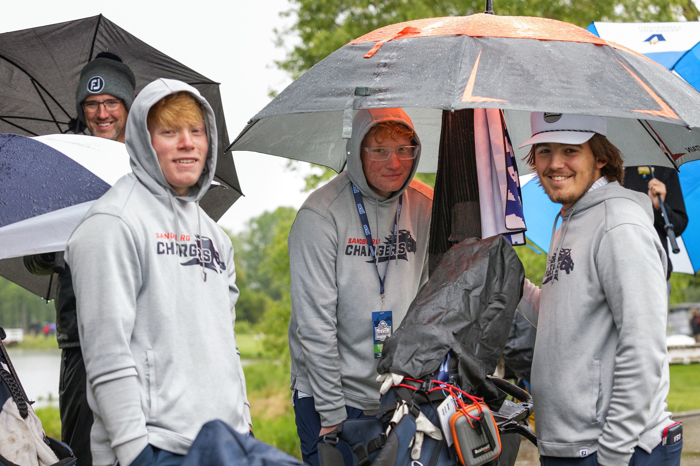 (L-R) Sandburg coach Ryan Twaddle and men's golfers Colby Robertson, Cooper Hansen and Tanner Wake try to stay dry during the second day of competition at the NJCAA Division II Men's Golf Championship at Swan Lake Resort in Plymouth, Ind.